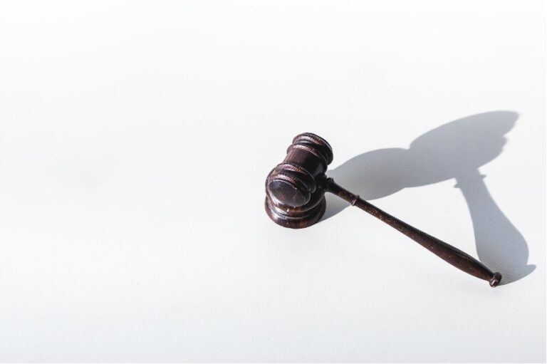 A wooden judge's gavel rests on a white surface, casting a distinct shadow, symbolizing the gravity of legal guardianship in Singapore.