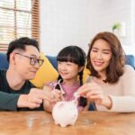 A family of 3 putting coins into a piggy family bank