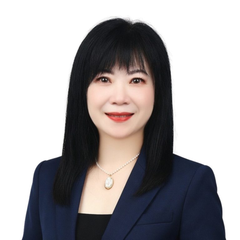 A woman with straight black hair, wearing a dark blazer, black top, and pearl necklace, smiles at the camera against a plain white background.